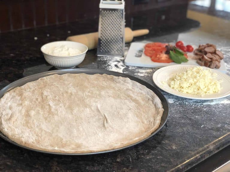 Pizza dough in a pan spread with sauce