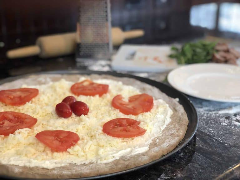 Tomato slices on a cheese pizza before baking
