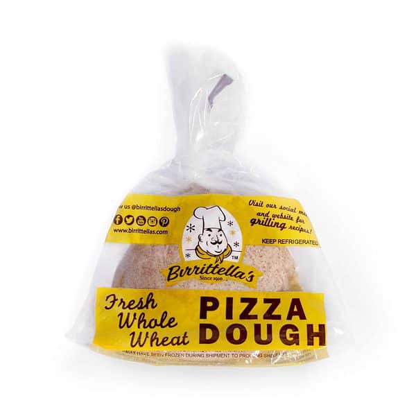 A bag of fresh whole wheat pizza dough on a white surface.