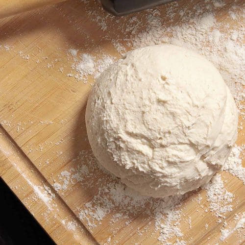 A ball of dough on a cutting board, perfect for recipes.