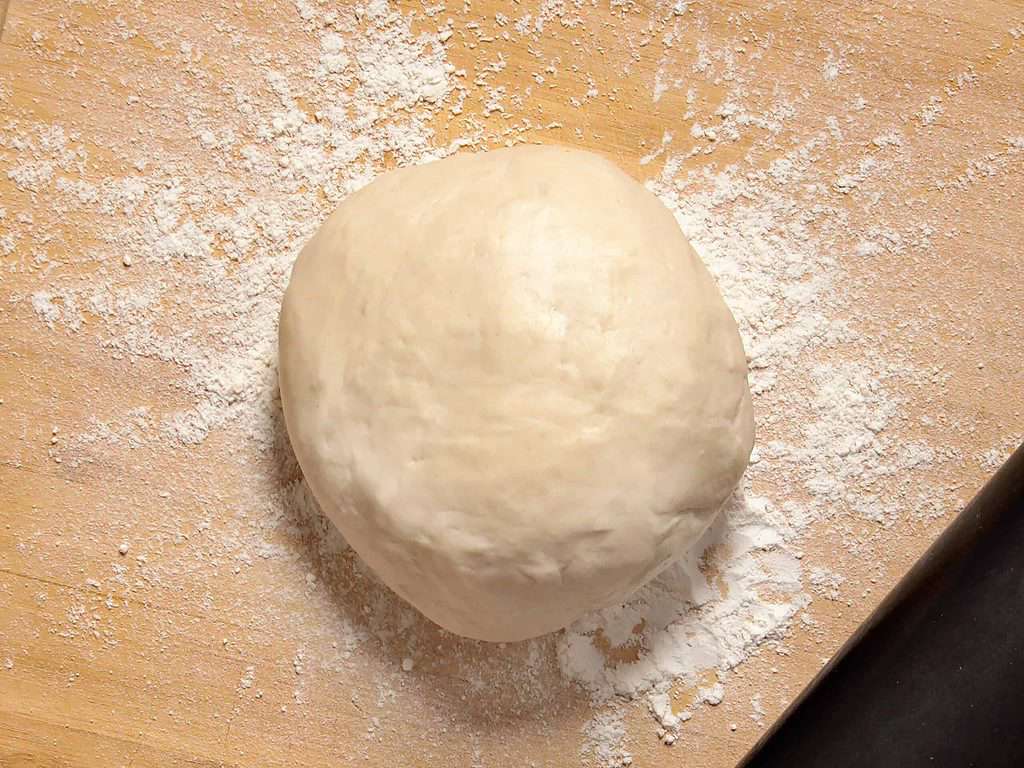 Recipes for a variety of dough-based dishes typically require a ball of dough to be prepared and placed on a wooden table.