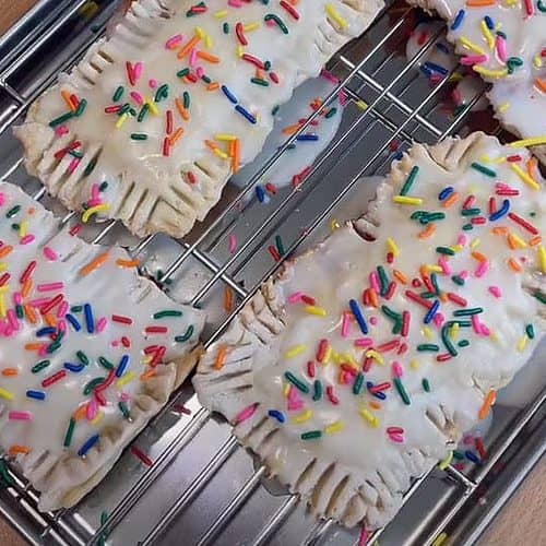 A tray of pastries with sprinkles on top.