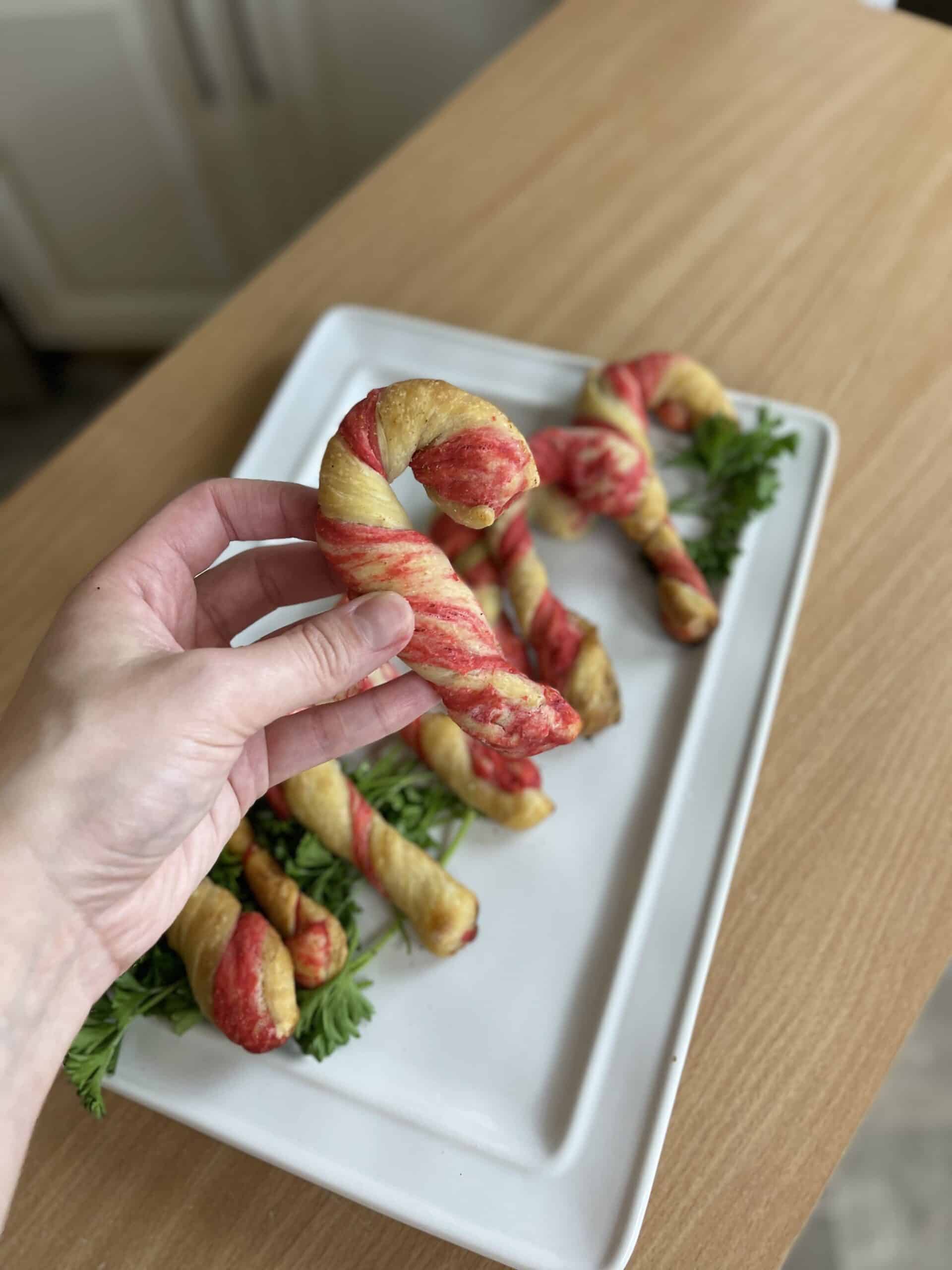 A person holding up a plate of twisted candy cane breadsticks.