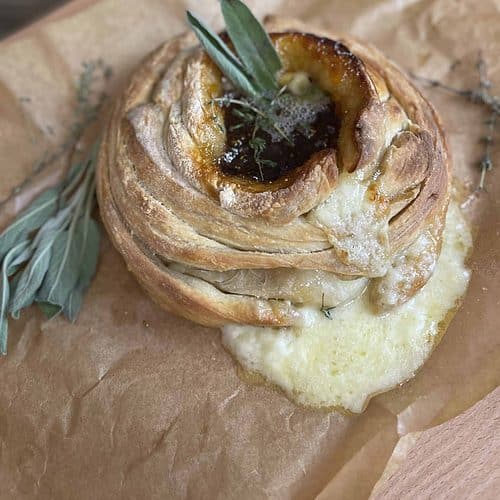A baked brie with a sprig of sage on top.