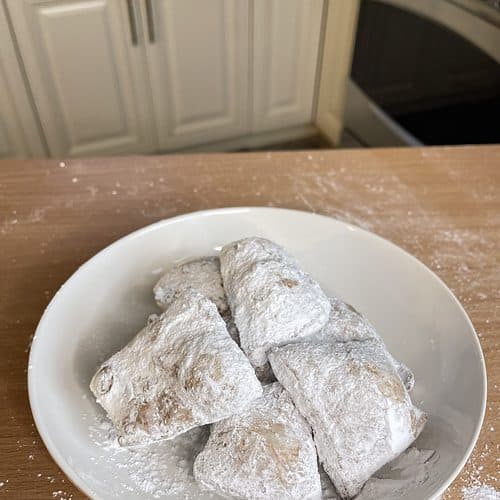 A plate of powdered beignets sitting on a table.