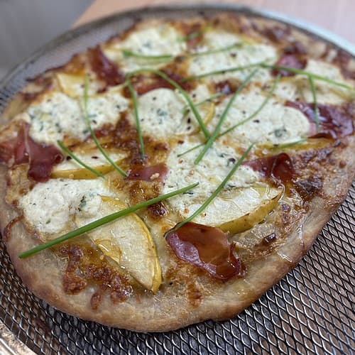 A pizza with cheese, honey, and apple on top.