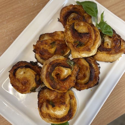 A plate with a bunch of Pepperoni Pinwheels on it.