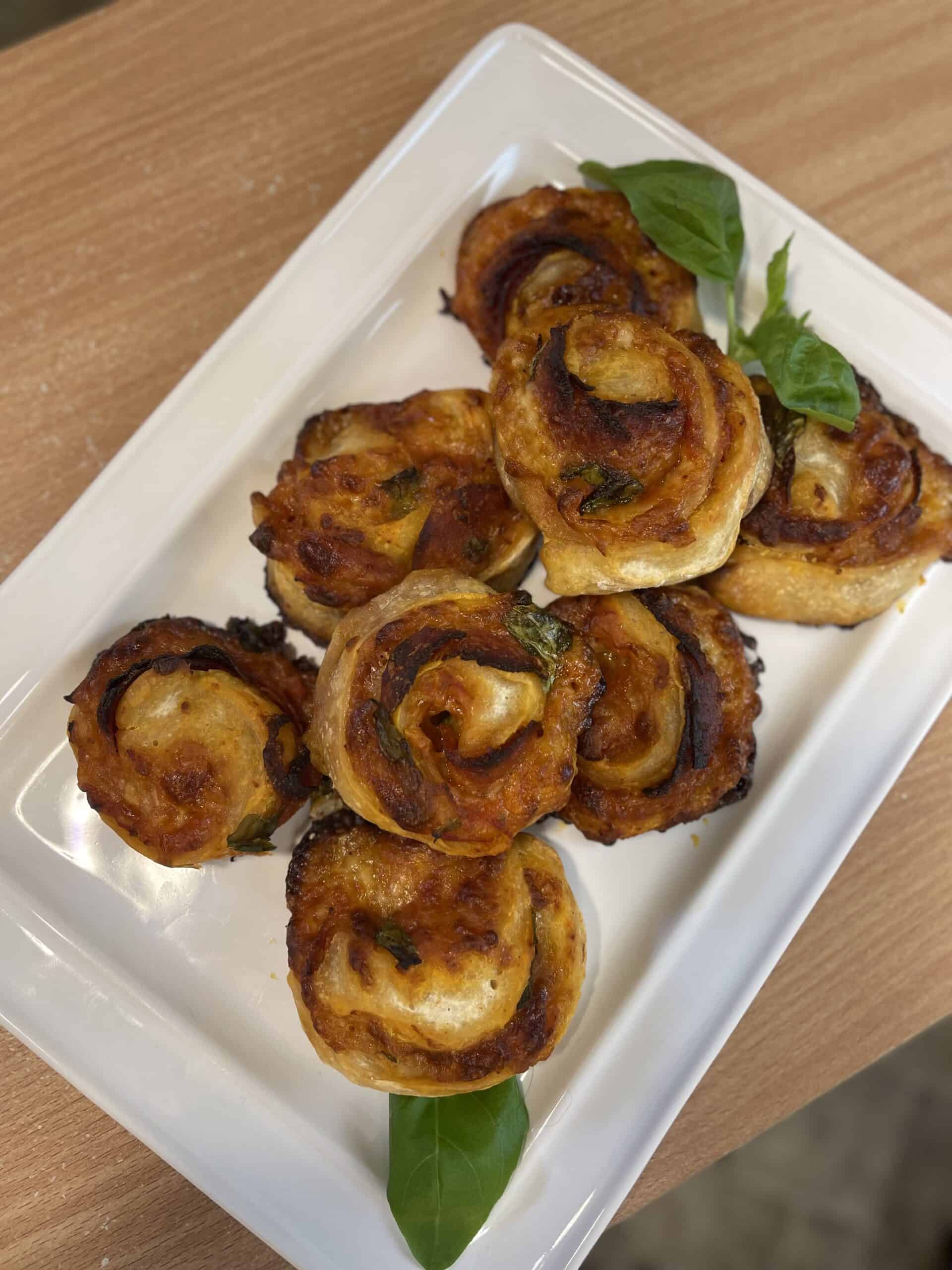 A plate with a bunch of Pepperoni Pinwheels on it.