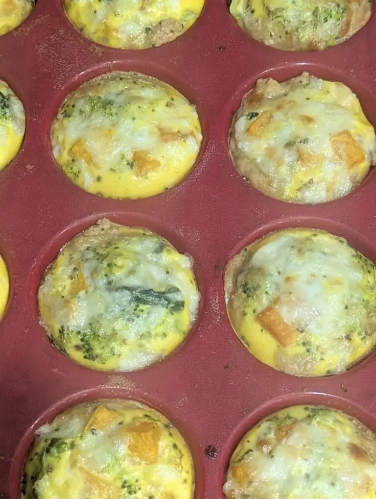 Golden baked breakfast cups in a muffin pan with set egg, melted cheese, butternut squash and broccoli.