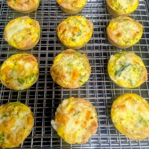 Twelve high protein breakfast cups made with Birrittella's protein rich pizza dough, filled with egg, butternut squash, broccoli and melted cheese, cooling on a wire rack.